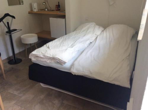 a bed with white sheets on it in a room at Klosterpensionen in Viborg