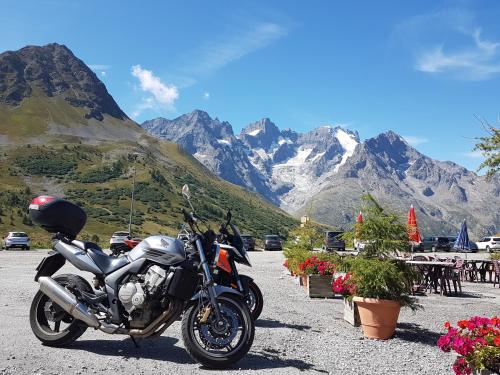 a motorcycle parked in a parking lot with mountains in the background at Chalet Solneige in Vaujany