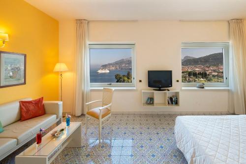 a hotel room with a bed and a couch and two windows at Hotel Bristol in Sorrento