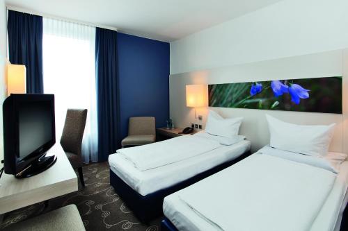 a hotel room with two beds and a tv at Concorde Hotel Siegen in Siegen