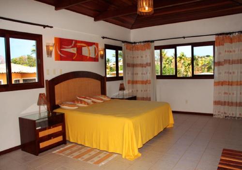 Schlafzimmer mit einem großen gelben Bett und Fenstern in der Unterkunft Lagoa Eco Village in Pipa