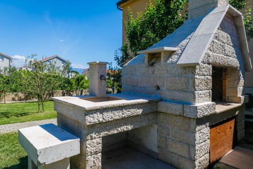 an outdoor pizza oven in a yard at Apartment Pirun in Baška