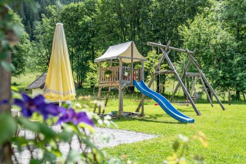 een park met een speeltuin met een glijbaan en een paraplu bij Bio Bauernhof Vorderoberlehen in Werfenweng