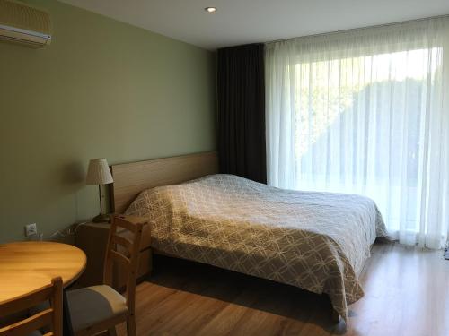 a bedroom with a bed and a table and a window at Atostogos Pervalkoje in Pervalka