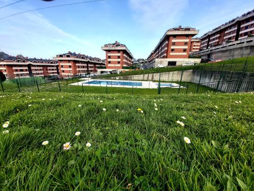pole trawy z basenem i budynkami w obiekcie CASTRO COSTA NORTE Apartamento Jardín Garaje w mieście Castro-Urdiales