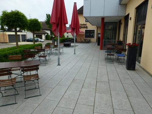 a patio with tables and chairs and red umbrellas at Hotel-Gasthof-Hirsch in Dellmensingen