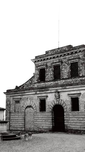 an old brick building with a large door and windows at Podere Pievina Delle Corti - Dimora di Campagna in Sinalunga