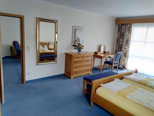 a bedroom with a bed and a desk and a mirror at Hotel Fortuna in Bad Gögging