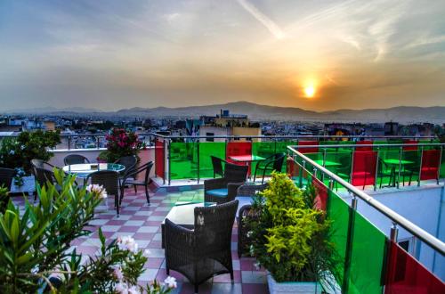 a balcony with tables and chairs and a view of a city at Attalos Hotel in Athens