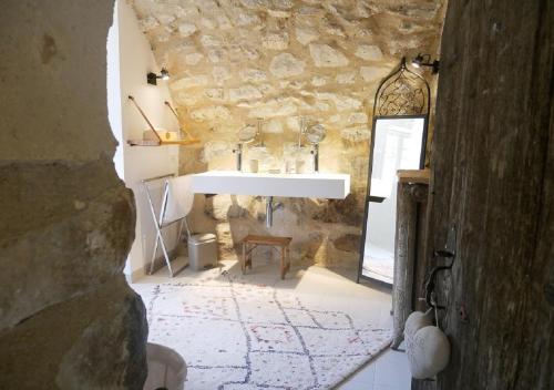 La salle de bains est pourvue d'un lavabo et d'un mur en pierre. dans l'établissement La Maison de Marguerite, à Montbrun-les-Bains