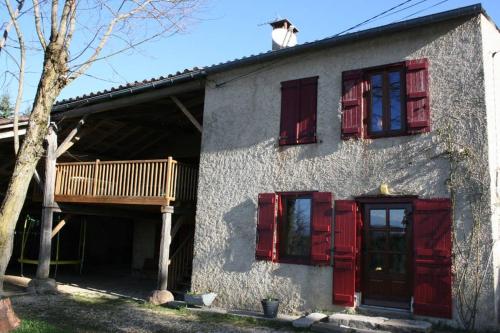 a house with red shuttered windows and a porch at La Fount del Fer in Camarade