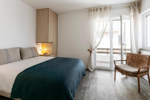 a bedroom with a bed and a chair and a window at Mare Cheia: Beach and Surf Apartment 2 in Consolacao