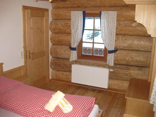 1 dormitorio con una pared de madera y una ventana en Bärenhütte Tröpolach-Nassfeld, en Jenig