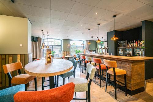 a bar with chairs and a table in a restaurant at Hotel & Eetk'fee de VLiK in Ospel