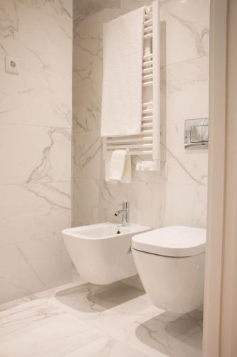 a white bathroom with a toilet and a sink at Feira Hostel & Suites in Santa Maria da Feira