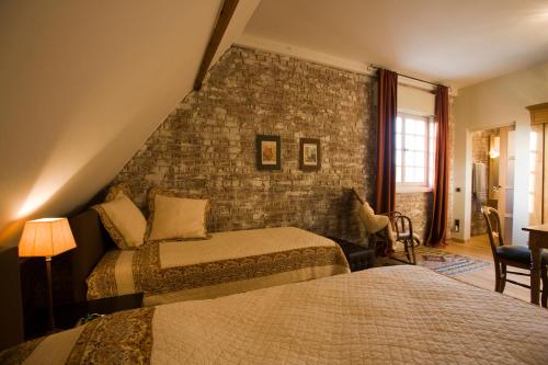 a bedroom with two beds and a brick wall at B&B Willow Lodge in De Pinte