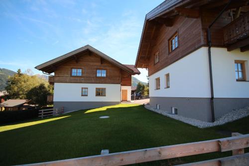 a house with a green yard next to a building at Ski in/Ski out Chalets Tauernlodge by Schladming-Appartements in Schladming