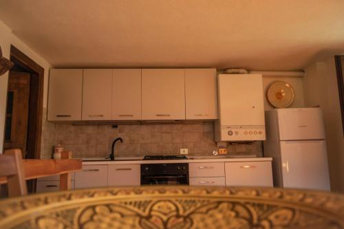 eine Küche mit weißen Schränken, einem Herd und einem Kühlschrank in der Unterkunft Nido delle aquile in Cogne