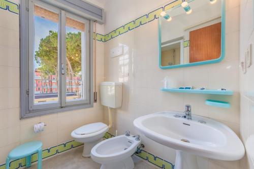 ein Bad mit einem Waschbecken, einem WC und einem Fenster in der Unterkunft Villa Delfa in Caorle