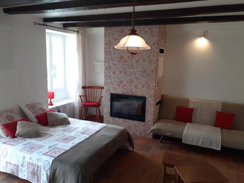 een slaapkamer met een bed en een open haard en een bank bij Le Petit Brétigny in Beaumont
