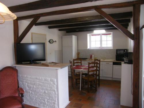 een keuken en eetkamer met een tv en een tafel bij Le Petit Brétigny in Beaumont