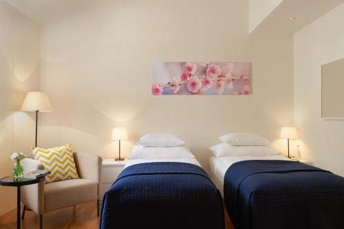 two beds in a room with a couch and a painting at Residence Vocelova in Prague