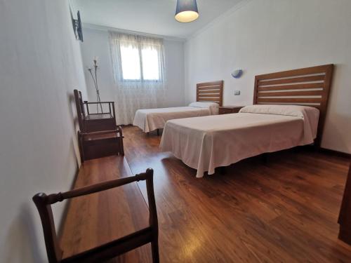 a room with two beds and a wooden table at Hotel Restaurante Dama de Baza in Baza