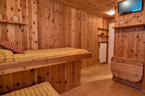 a log cabin bedroom with a bunk bed and a flat screen tv at Chesa Pradatsch Sur - Celerina in Celerina