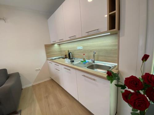 a kitchen with white cabinets and a sink and red roses at Apartments & Rooms Mostar Story in Mostar