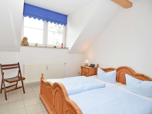 two beds in a bedroom with a chair and a window at Ferienhaus Lobbe - WG 02 über zwei Etagen, strandnah in Lobbe
