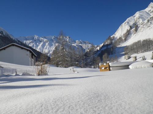 a snow covered field with a building and mountains at Apart-Garni Motnaida in Samnaun