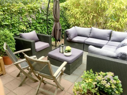a patio with a couch and chairs and an umbrella at Cottage Markdal in Breda
