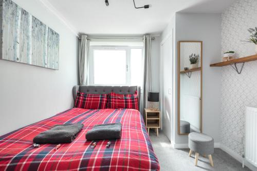 a bedroom with a red plaid bed with two pillows on it at City Centre Stylish Apartment With Free Parking in Edinburgh