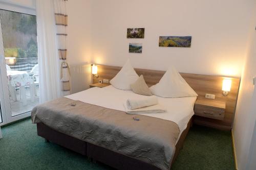 a bedroom with a bed with white sheets and a window at Wein und Gästehaus Scheid in Sankt Aldegund