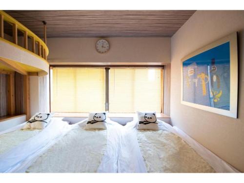 a bedroom with a large bed with pillows with a clock at BEYOND HOTEL Takayama 2nd - Vacation STAY 82237 in Takayama