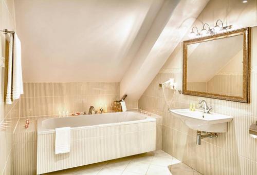 een badkamer met een bad, een wastafel en een spiegel bij Hotel Kazimierski Zdrój in Janowiec