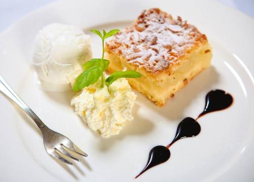a white plate with two pieces of cake and two spoons at Hotel Kazimierski Zdrój in Janowiec