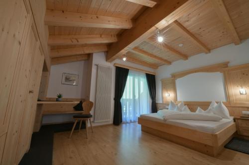 a bedroom with a large bed in a room with wooden ceilings at Garni Sunela B&B in Selva di Val Gardena