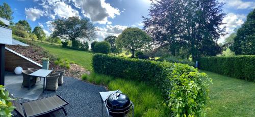 a garden with a table and chairs and a hedge at Sakura Lodging in Bossut-Gottechain