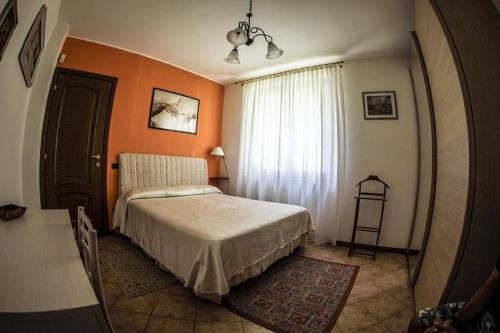 - une chambre avec un lit et un mur orange dans l'établissement Alla Camelia B&B, à Brunello