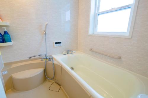 ein weißes Bad mit einer Badewanne und einem Fenster in der Unterkunft Minamitsuru-gun - House - Vacation STAY 82283 in Fujikawaguchiko