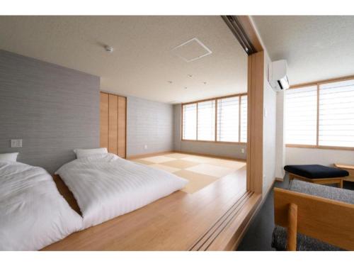 een slaapkamer met een wit bed en een houten vloer bij BEYOND HOTEL Takayama 3rd - Vacation STAY 82217 in Takayama