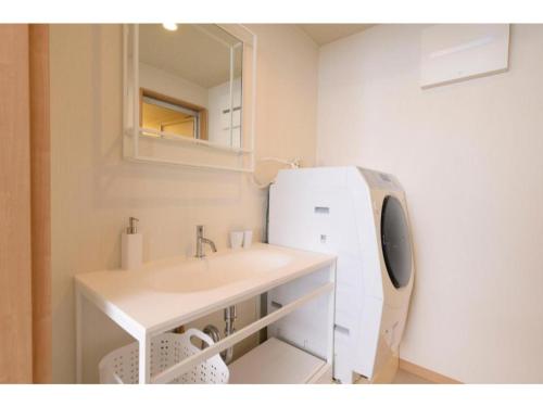 een witte badkamer met een wastafel en een spiegel bij BEYOND HOTEL Takayama 3rd - Vacation STAY 82217 in Takayama