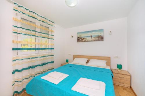 a bedroom with a blue bed and a window at Apartments EcoNature in Virpazar