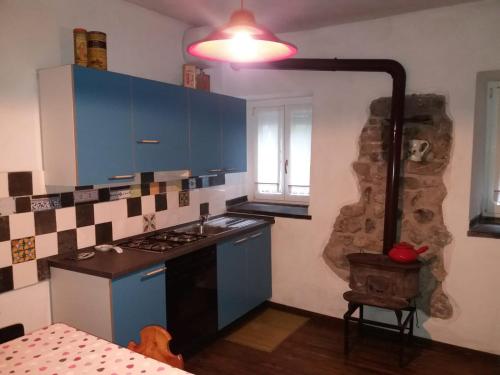 uma cozinha com armários azuis e um forno com placa de fogão em La casa di Nonna Nilla em San Giovanni Bianco