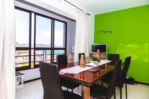 une salle à manger avec des murs verts, une table et des chaises dans l'établissement Criola Maison, à Mindelo