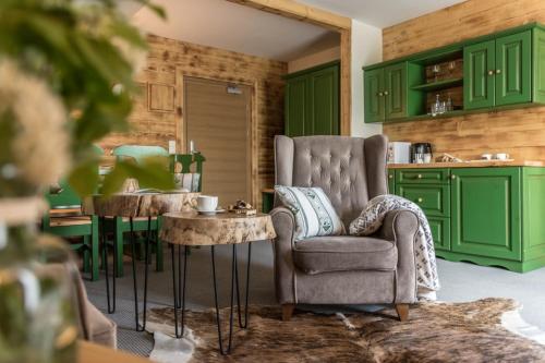 a kitchen with green cabinets and a chair and a table at Villa Adamo & Relax in Zakopane