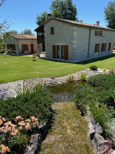 a stone house with a pond in front of it at La petite maison dans le Quercy in Cayriech