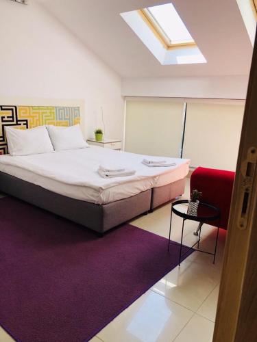 a bedroom with a large bed and a red chair at Executive Rooms and Suites Play in Veliko Tŭrnovo