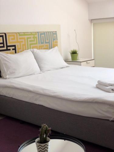 a bedroom with a large white bed with a cactus on a table at Executive Rooms and Suites Play in Veliko Tŭrnovo